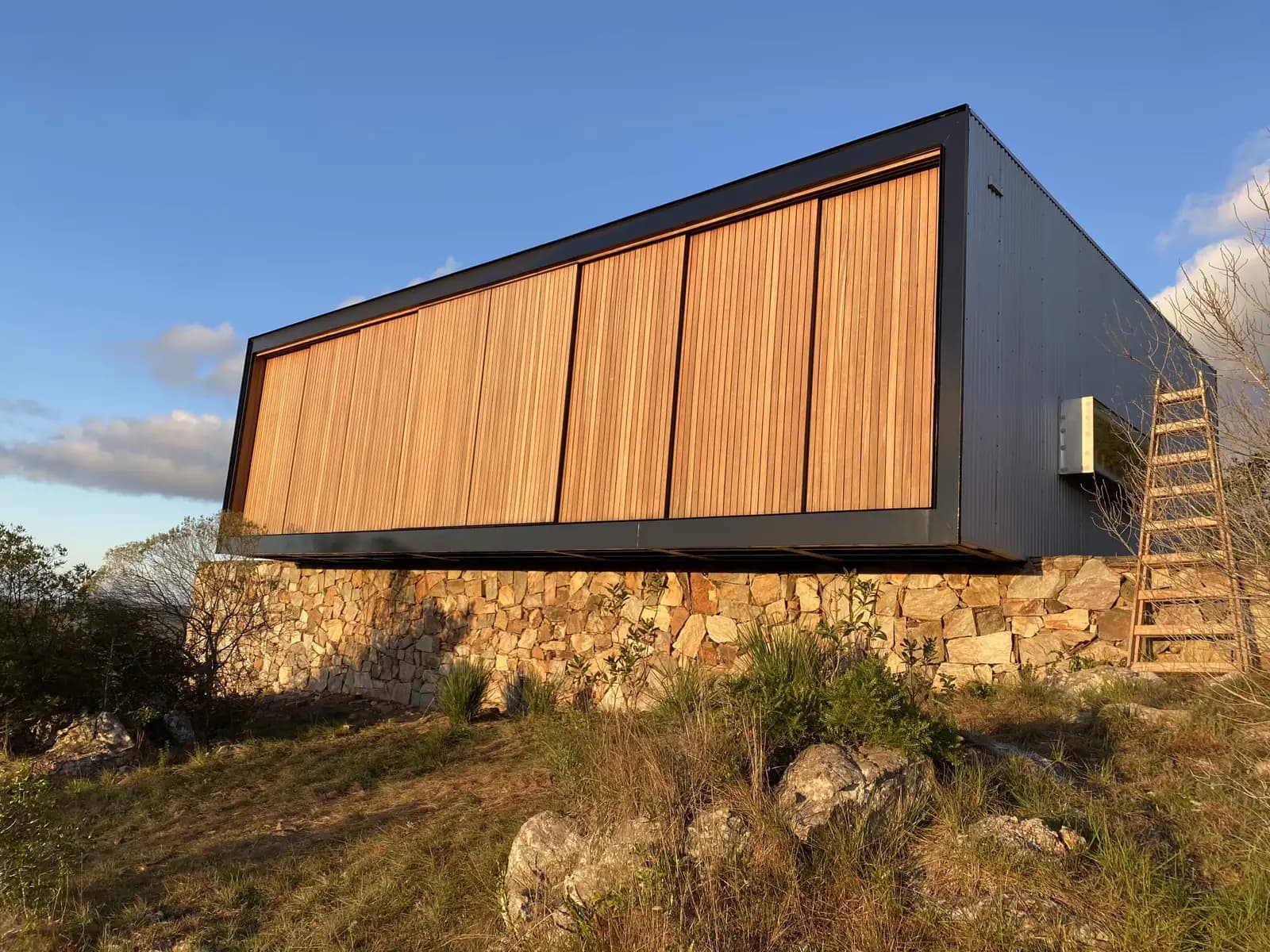 Cabaña de diseño con revestimiento exterior negro y celosías de madera