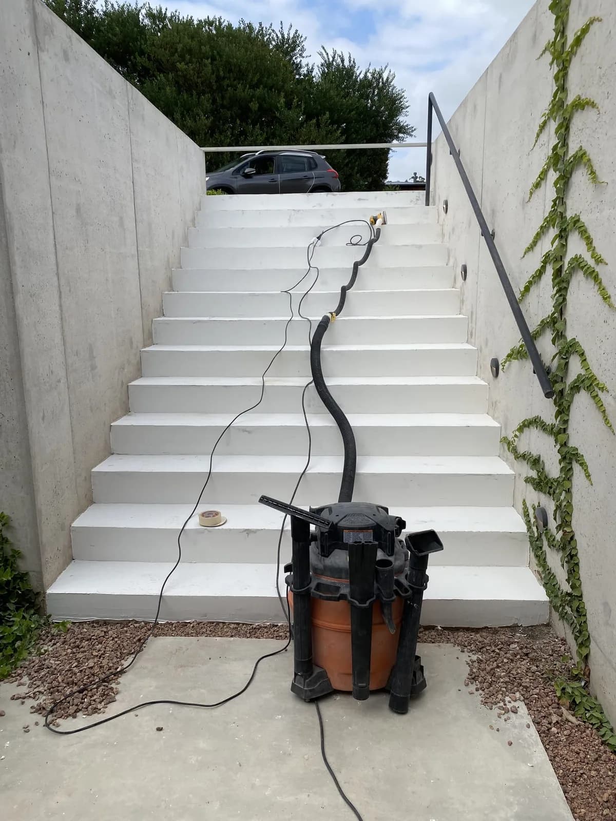 Escalera exterior de hormigón pintada de blanco, con la lijadora de la preparación