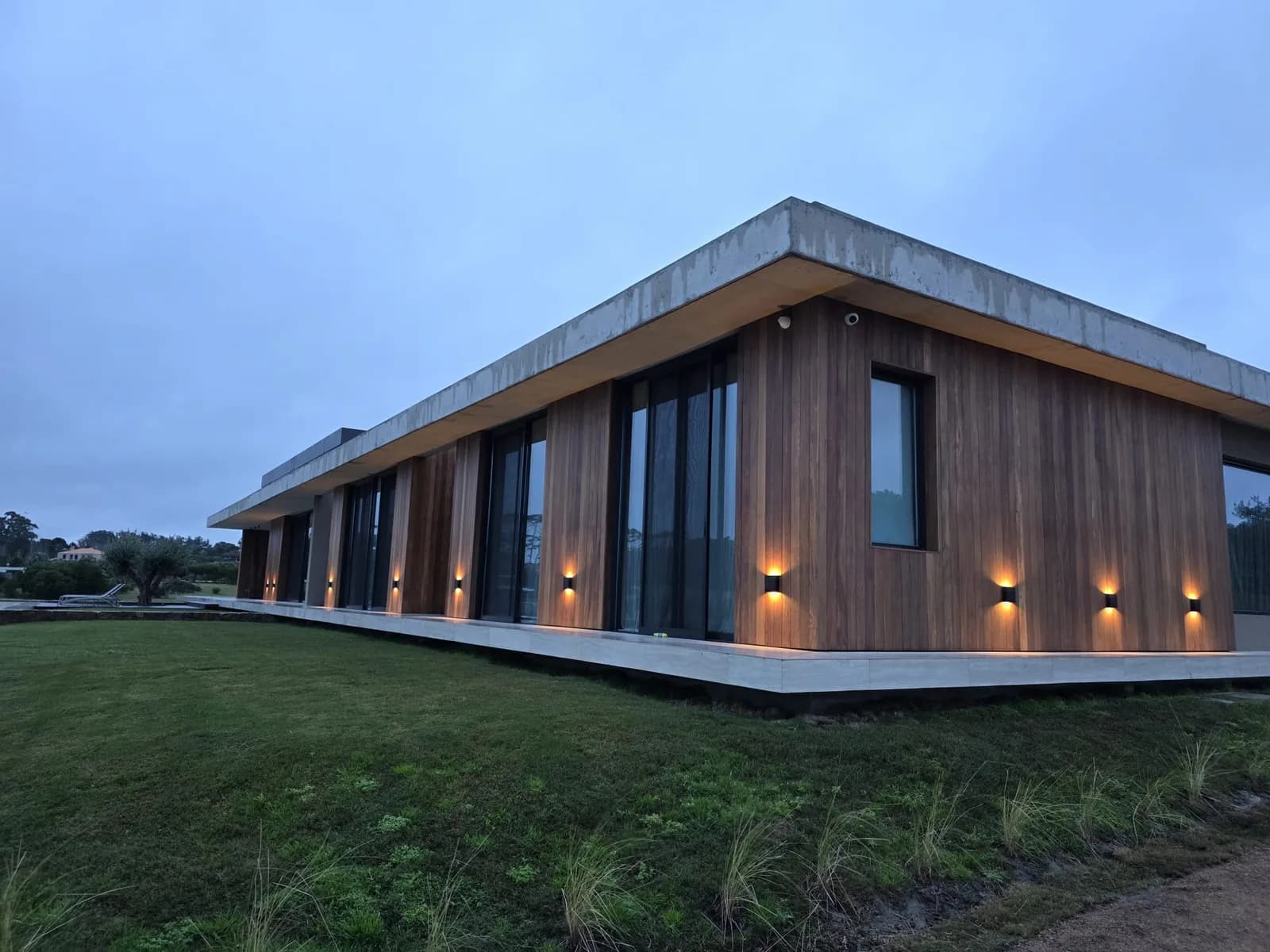 Residencia moderna con revestimiento de madera y fachada iluminada al atardecer